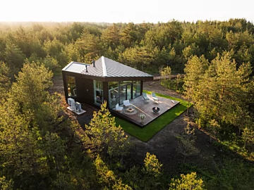 Modern outdoor living space with the contemporary Mix 850 fire pit creating warmth and atmosphere on a patio beside a glass-walled home